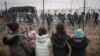 Migrant children stand in front of a barbed wire fence and Polish servicemen on the Belarusian side of Poland's Kuznitsa checkpoint on November 17, 2021, as reports first surfaced of the migrants' withdrawal from the area, under Belarusian forces' supervision. 