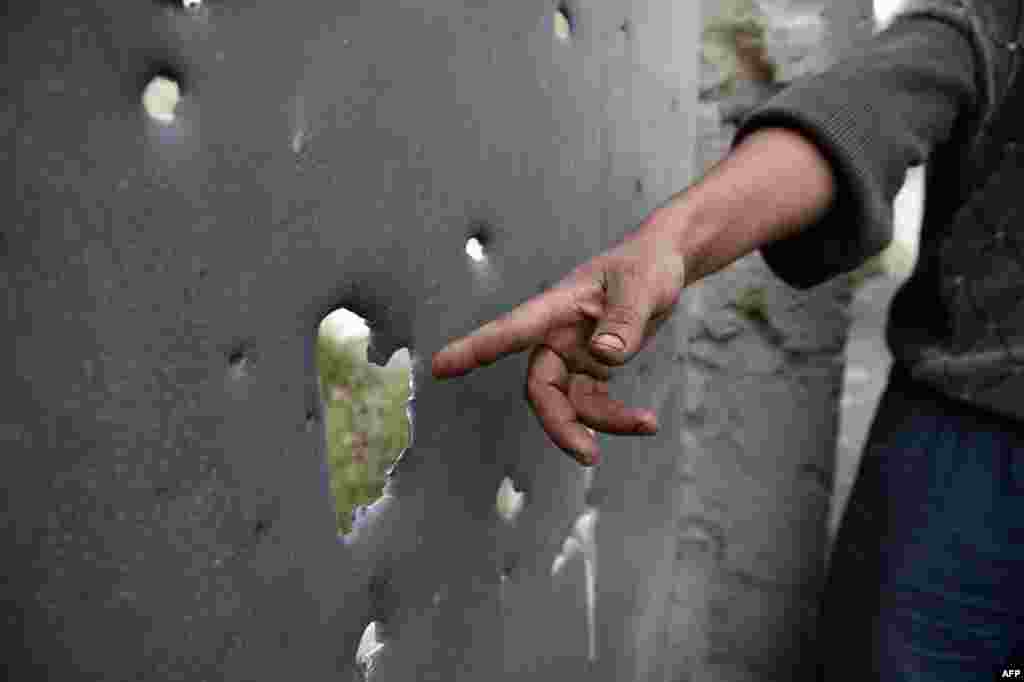 A resident of the Azerbaijani town of Tartar, north of Nagorno-Karabakh, shows apparent shell damage to another gate.&nbsp;